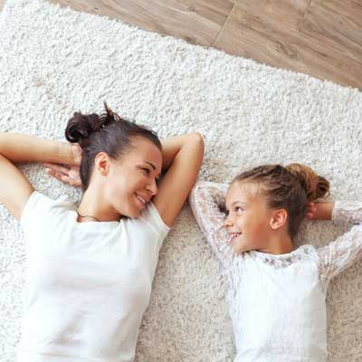 Mother and daughter laying down on clean carpet